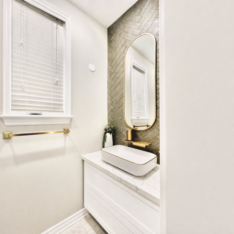 Modern bathroom vanity with herringbone tile accent wall, gold mirror and vessel sink.
